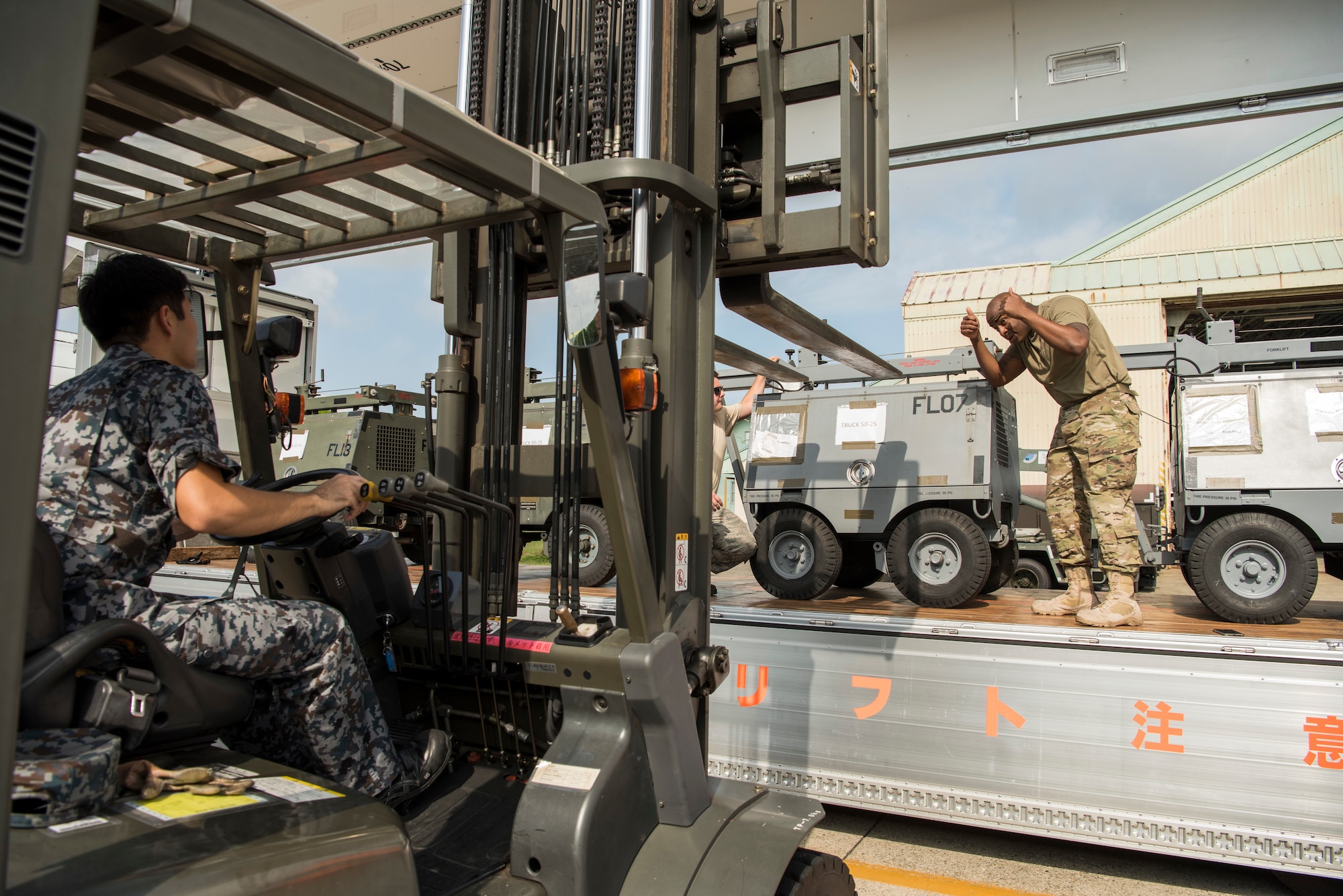 U.S. Air Force Staff Sgt. Edwin Long, a 35th Logistic Readiness Squadron traffic management office outbound cargo supervisor, gives a Japan Air Self-Defense Force member a thumbs up while unloading cargo during an aviation training relocation at Komatsu Air Base, Japan, Sept. 30, 2019. During the week-long exercise, participants facilitated F-16 maintenance training, communication practice and bilateral maintenance equipment sharing. (U.S. Air Force photo by Senior Airman Collette Brooks)