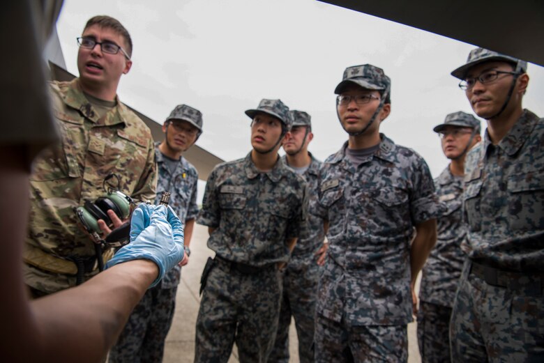 U.S. Air Force Senior Airman Gabriel Contreras, a 13th Aircraft Maintenance Unit crew chief, shows members of the Japan Air Self-Defense Force a magnetic chip detector during an aviation training relocation at Komatsu Air Base, Japan, Oct. 2, 2019. U.S. Airmen trained JASDF counterparts on the inner workings of the F-16 Fighting Falcon to increase the knowledge and interaction of the jet enhancing operation cohesion. (U.S. Air Force photo by Senior Airman Collette Brooks)