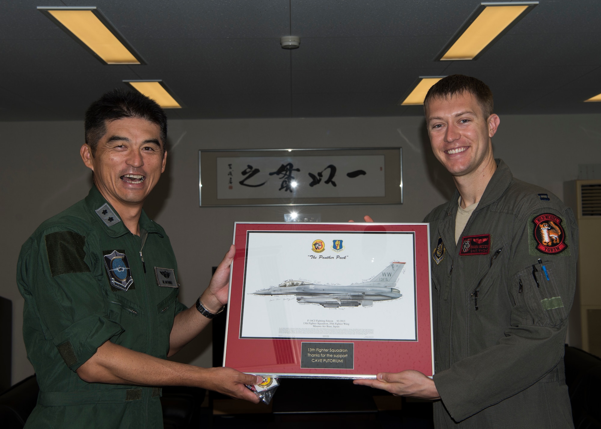 Japan Air Self-Defense Force Maj. Gen. Masahito Monma, the Japan Air Self-Defense Force 6th Air Wing commander, and U.S. Air Force Capt. Phillip McCoy, a 13th Fighter Squadron F-16 Fighting Falcon pilot, poses for a photo with an F-16 framed photo during an aviation training relocation at Komatsu Air Base, Japan, Sept. 30, 2019. McCoy presented Monma this item as a gift to express his gratitude toward JASDF’s hospitability, support and friendship. (U.S. Air Force photo by Senior Airman Collette Brooks)