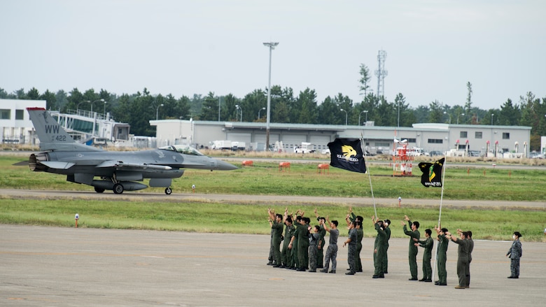 Members of the Japan Air Self-Defense Force waves at a 35th Fighter Wing F-16 Fighting Falcon pilot, during an aviation training relocation at Komatsu Air Base, Japan, Oct. 3, 2019. JASDF members remained on the flight line with squadron flags and smiles to say goodbye to each F-16 pilot prior to the conclusion and final sortie of the exercise. (U.S. Air Force photo by Senior Airman Collette Brooks)