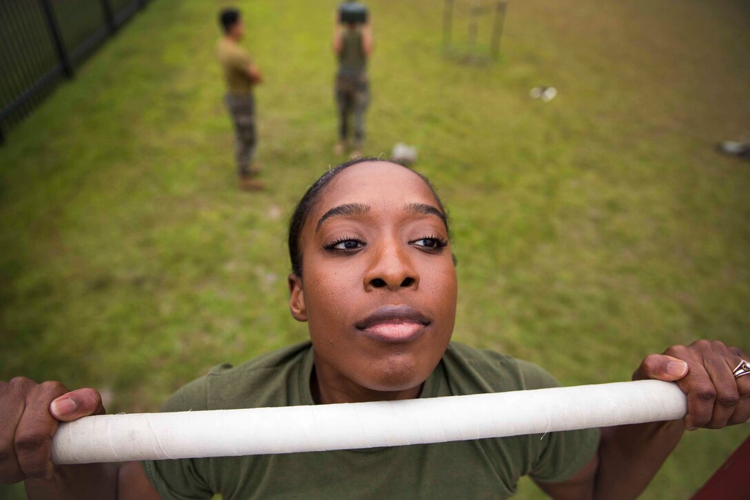 Sgt. Abeo Johnson an administrative clerk with II Marine Expeditionary Force Information Group, poses for a photo while doing pull ups at Camp Lejeune, N.C., Oct. 10, 2019. "We're all on the same team," said Johnson, a East Orange, N.J., native. According to her leadership, Johnson provides excellent support for Marines who deploy and assist any Marines who were injured on deployment. Additionally, she ensures Marines are taken care of and teaches them every chance she gets. Johnson displays nothing short of what is expected when it comes to being a leader of Marines. (U.S. Marine Corps photo by Cpl. Caleb T. Maher)