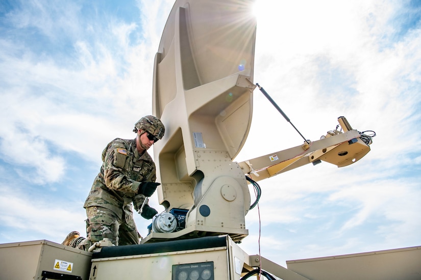 Soldier sets up satellite dish.