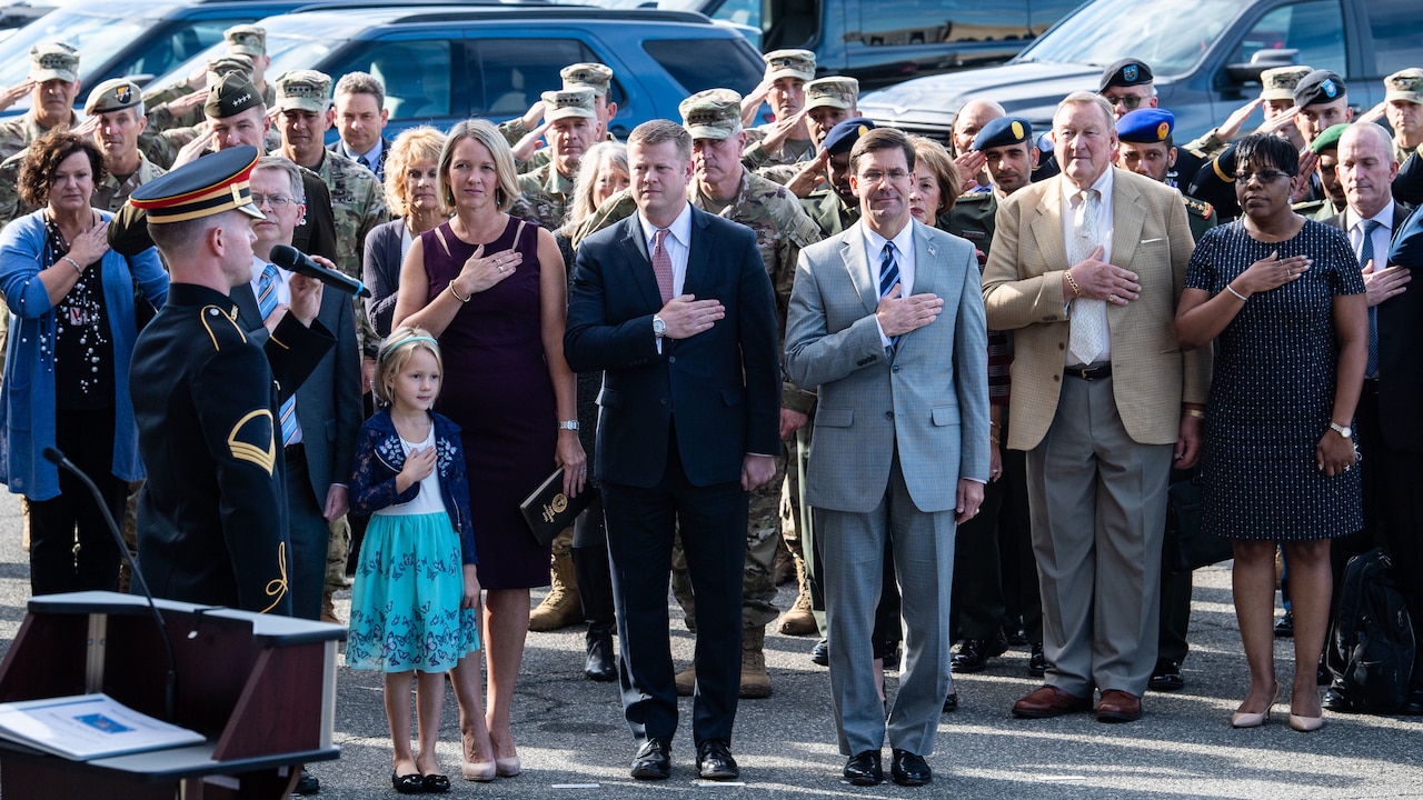 Defense Secretary Dr. Mark T. Esper and other people hold their hands over the hearts.
