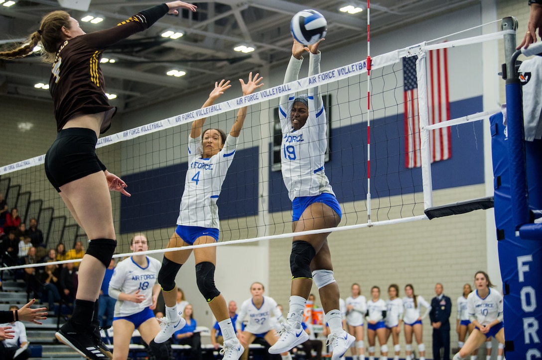 USAF cadets jump to block a spike during a volleyball match