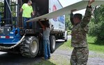 Soldier and contractor load lumber into a truck.