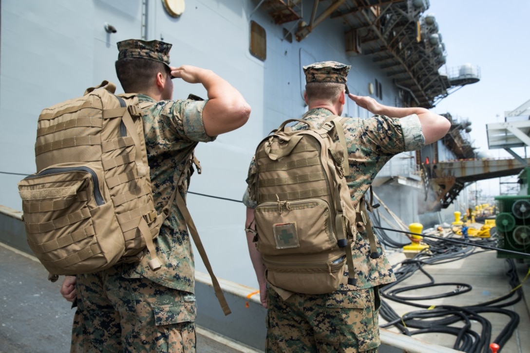 U.S. Marine Corps Lance Cpl. Jose Elias, left, and U.S. Navy Petty Officer 3rd Class Justin Chandler, right, both currently assigned to Special Purpose Marine Air Ground Task Force – WASP, render salutes before boarding the USS Wasp (LHD 1) on Naval Base San Diego, Sept. 22, 2019.