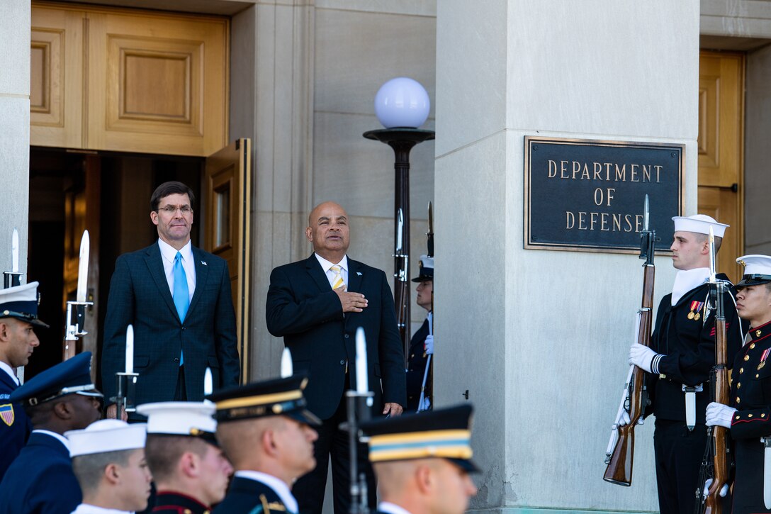 Two officials listen to national anthem at welcome ceremony.