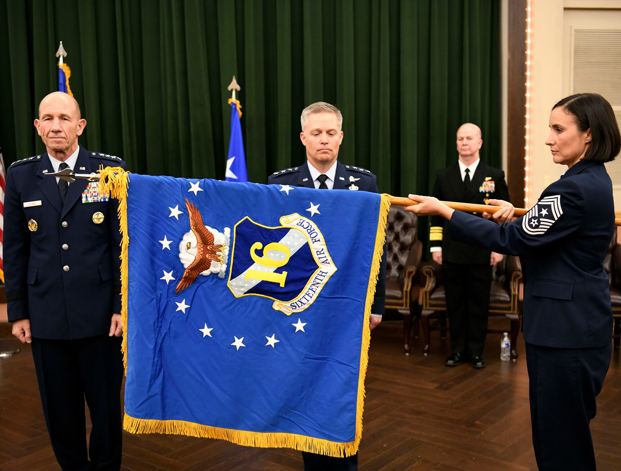 Chief Master Sgt. Summer Leifer, Sixteenth Air Force command chief, unfurls the Sixteenth Air Force flag to signify its activation, as Gen. Mike Holmes, commander of Air Combat Command, and Lt. Gen. Timothy Haugh, former commander of Twenty-Fifth Air Force, look on during the Sixteenth Air Force Assumption of Command at Joint Base San Antonio-Lackland, Texas, Oct. 11, 2019. Twenty-Fourth Air Force was also inactivated during the ceremony to integrate into the new information warfare Numbered Air Force. Sixteenth Air Force is responsible for providing IW capabilities to combatant commanders with the speed to match today’s technological environment. (U.S. Air Force photo by Tech. Sgt. R.J. Biermann)