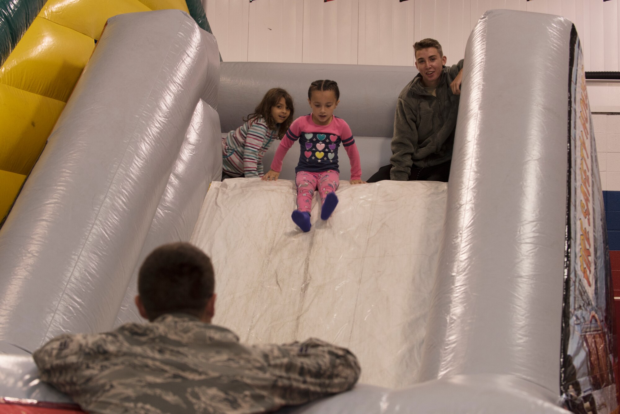Airman Andrew Tassey, a member of the Fire and Emergency Services Team at Whiteman Air Force Base, Missouri, supervises Whiteman Elementary first graders as they slide down a bouncy house slide on October 10, 2019. The 2019 Fire Prevention Week campaign theme is "Not Every Hero Wears a Cape. Plan and Practice Your Escape". (U.S. Air Force photo by Staff Sgt. Kayla White)