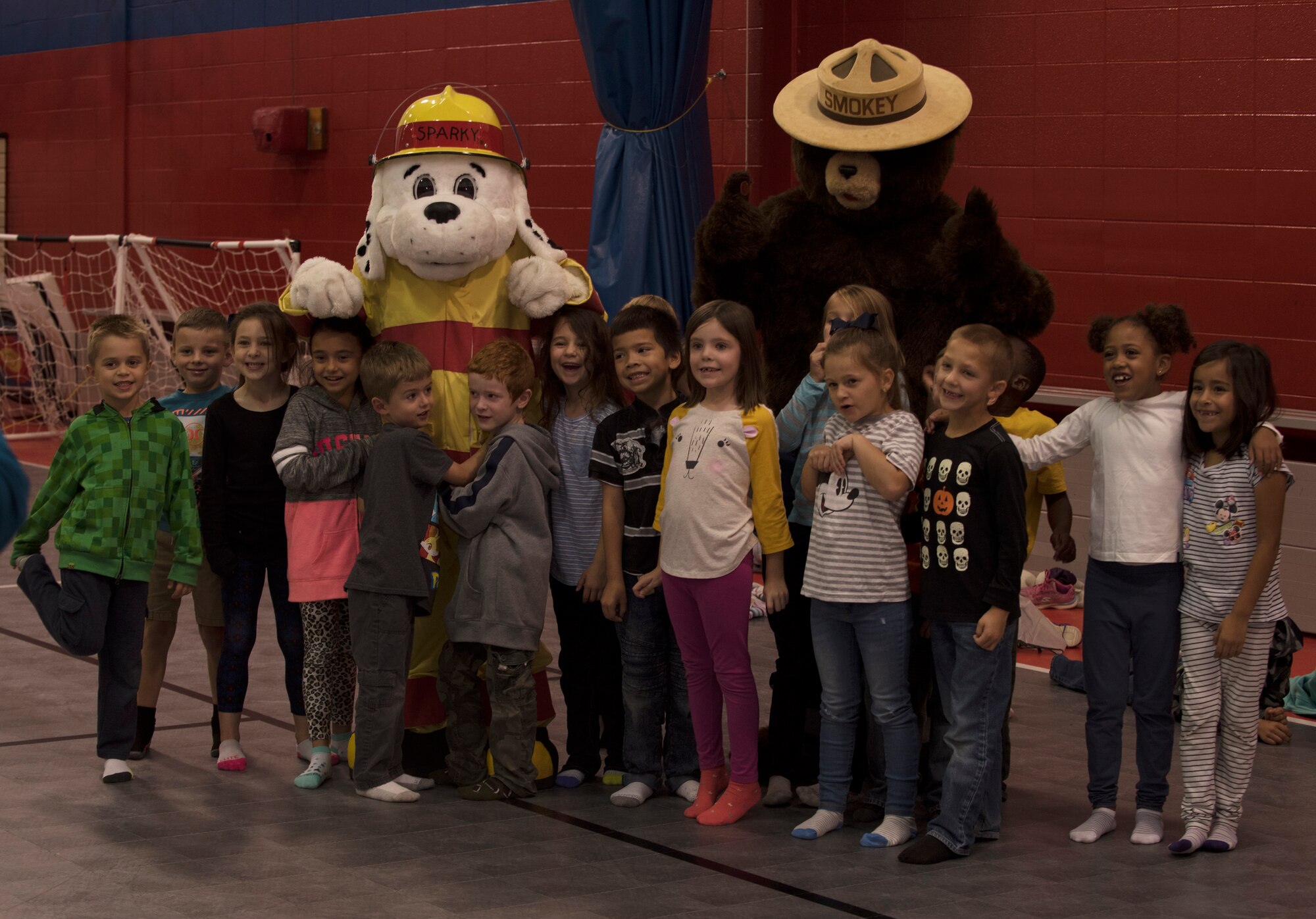 Sparky the Dog and Smokey the Bear, mascots for the Fire and Emergency Services Team at Whiteman Air Force Base, Missouri, pose for a photo with first graders from Whiteman Elementary on October 10, 2019. The 2019 Fire Prevention Week campaign theme is "Not Every Hero Wears a Cape. Plan and Practice Your Escape". (U.S. Air Force photo by Staff Sgt. Kayla White)