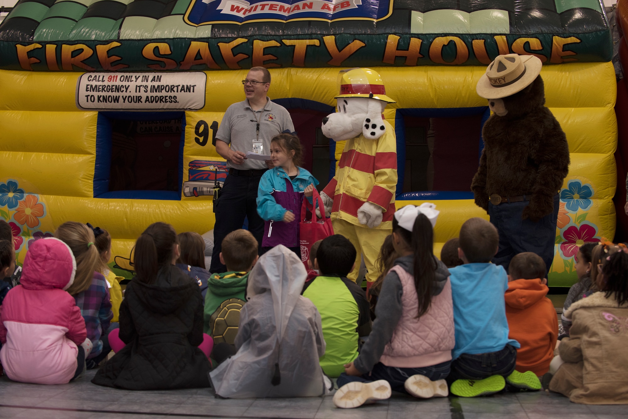 Andrew wells, a fire inspector assigned to the Fire and Emergency Services Team at Whiteman Air Force Base, Missouri, presents a prize bag to Madison Sprouls, a first grader from Whiteman Elementary on October 10, 2019, at the Youth Center. The 2019 Fire Prevention Week campaign theme is "Not Every Hero Wears a Cape. Plan and Practice Your Escape". (U.S. Air Force photo by Staff Sgt. Kayla White)