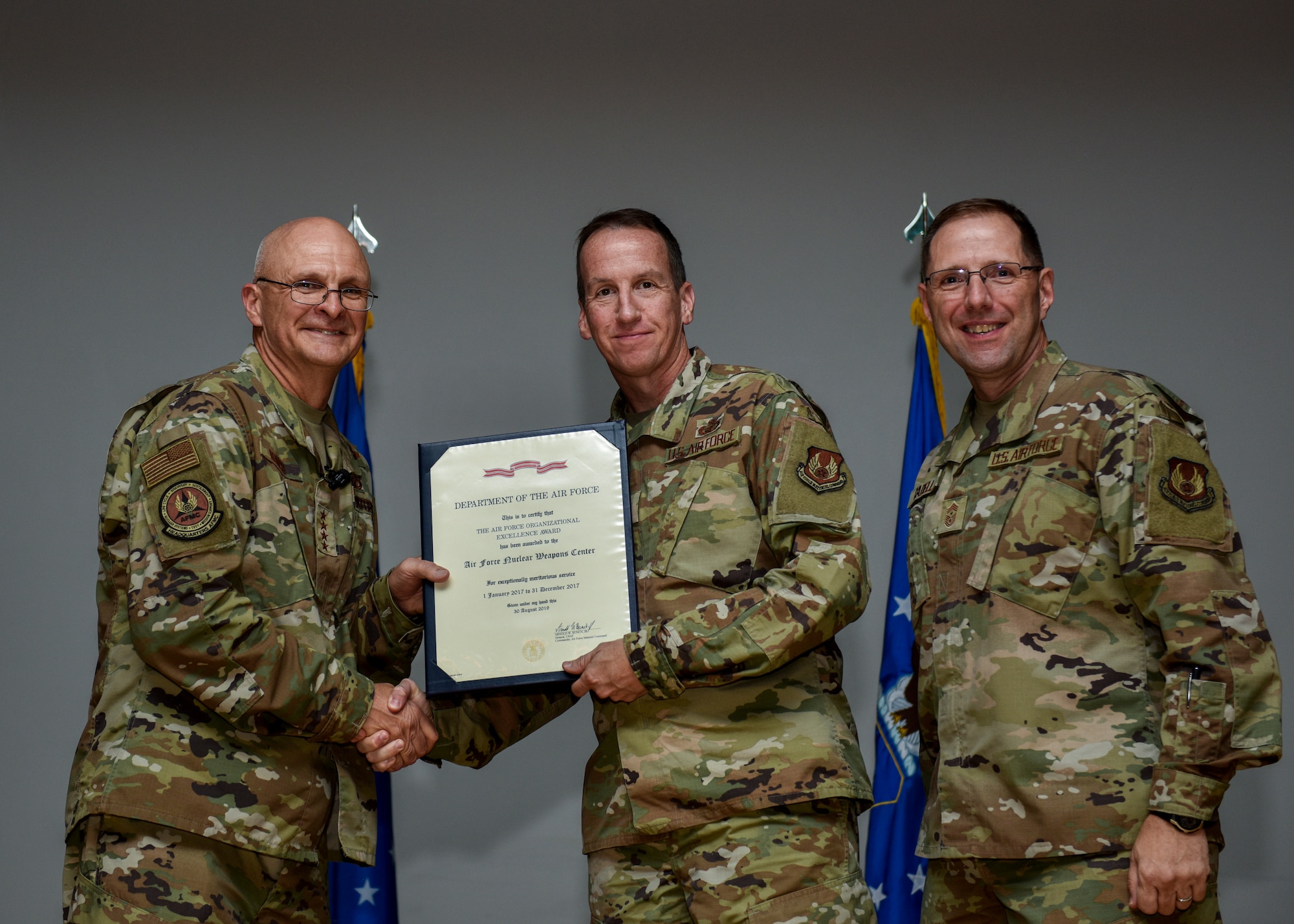 Air Force Materiel Command’s commander, Gen. Arnold W. Bunch, Jr., (left), shakes hands with Maj. Gen. Shaun Q. Morris, Air Force Nuclear Weapons Center commander, as he presents him with the center’s sixth Air Force Organizational Excellence award on Sept. 11, 2019, at Kirtland AFB, New Mexico. Chief Master Sgt. Stanley Cadell (right), AFMC command chief, also congratulated the center for its accomplishment. The 2018 award is for the 2017 calendar year, which marks the ninth consecutive year the center has received the award since its inception in March 2006. (U.S. Air Force photo by Airman 1st Class Austin J. Prisbrey)