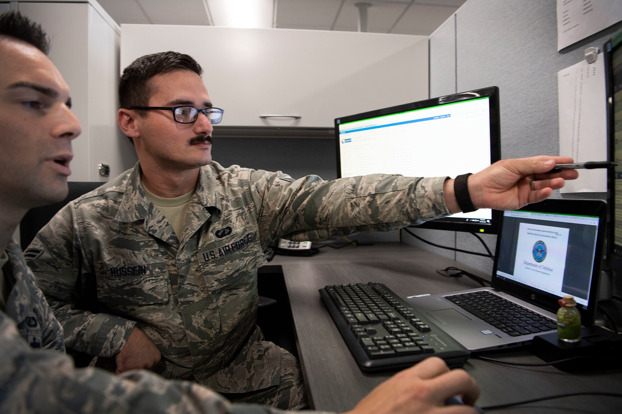 Airman 1st Class Aws Hussein, 66th Comptroller Squadron financial management technician, points to a computer screen while reviewing operating procedures with Staff Sgt. Josh Pimentel, 66 CPTS financial management supervisor, on Hanscom Air Force Base, Massachusetts, Oct. 10. Hussein served as an interpreter for U.S. troops in Iraq before immigrating to the U.S. in 2013.