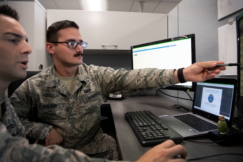 Airman 1st Class Aws Hussein, 66th Comptroller Squadron financial management technician, points to a computer screen while reviewing operating procedures with Staff Sgt. Josh Pimentel, 66 CPTS financial management supervisor, on Hanscom Air Force Base, Massachusetts, Oct. 10. Hussein served as an interpreter for U.S. troops in Iraq before immigrating to the U.S. in 2013.