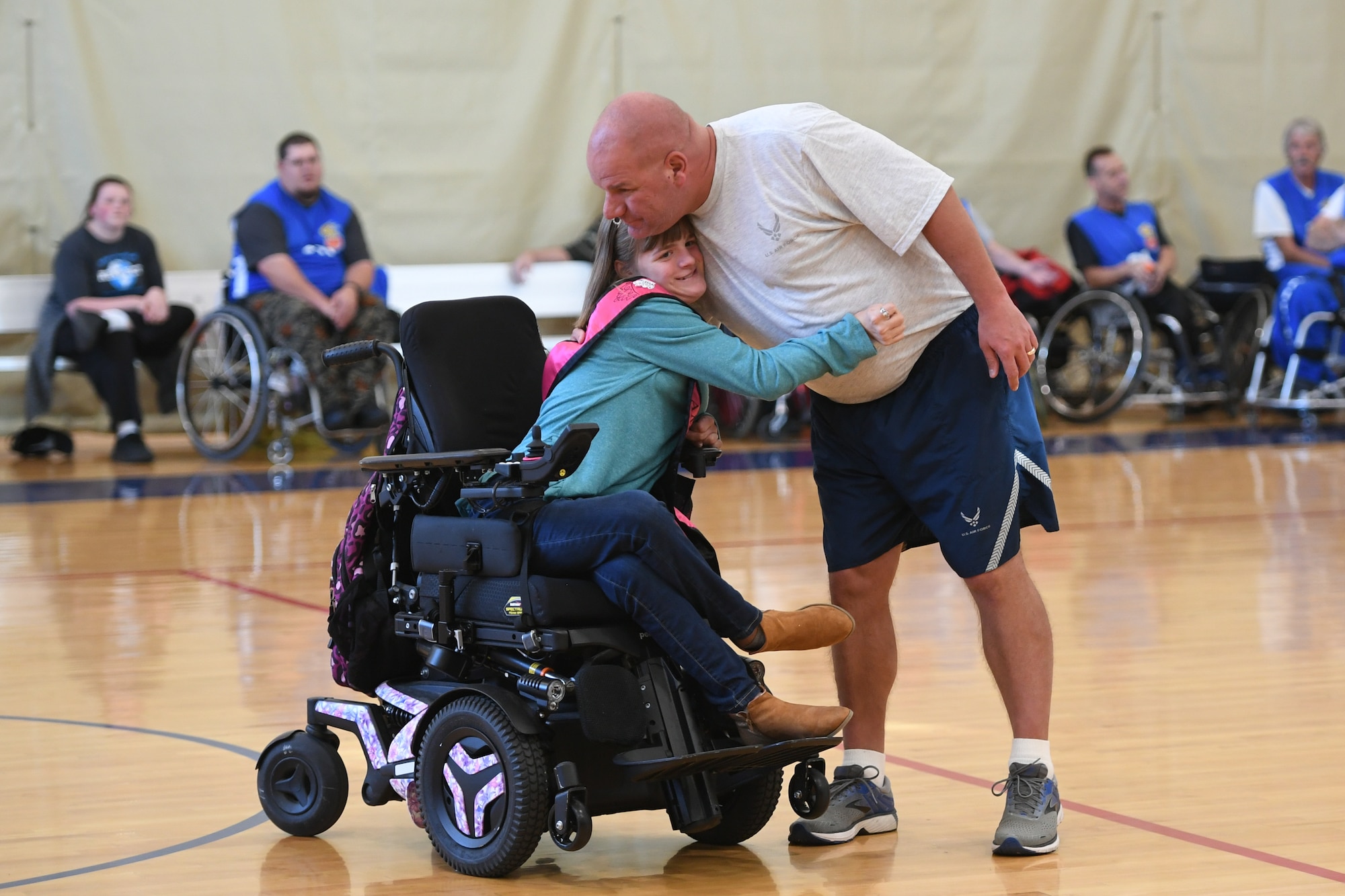 Master Sgt. Scott Heim, 388th Maintenance Squadron, hugs his daughter Brianna during halftime while being introduced as one of the basketball players who has an exceptional family member. Leaders from Hill's units faced off against the Ogden Wheelin' Wildcats, a semi-professional wheelchair basketball team, to celebrate National Disability Employment Awareness Month. (U.S. Air Force photo by Cynthia Griggs)