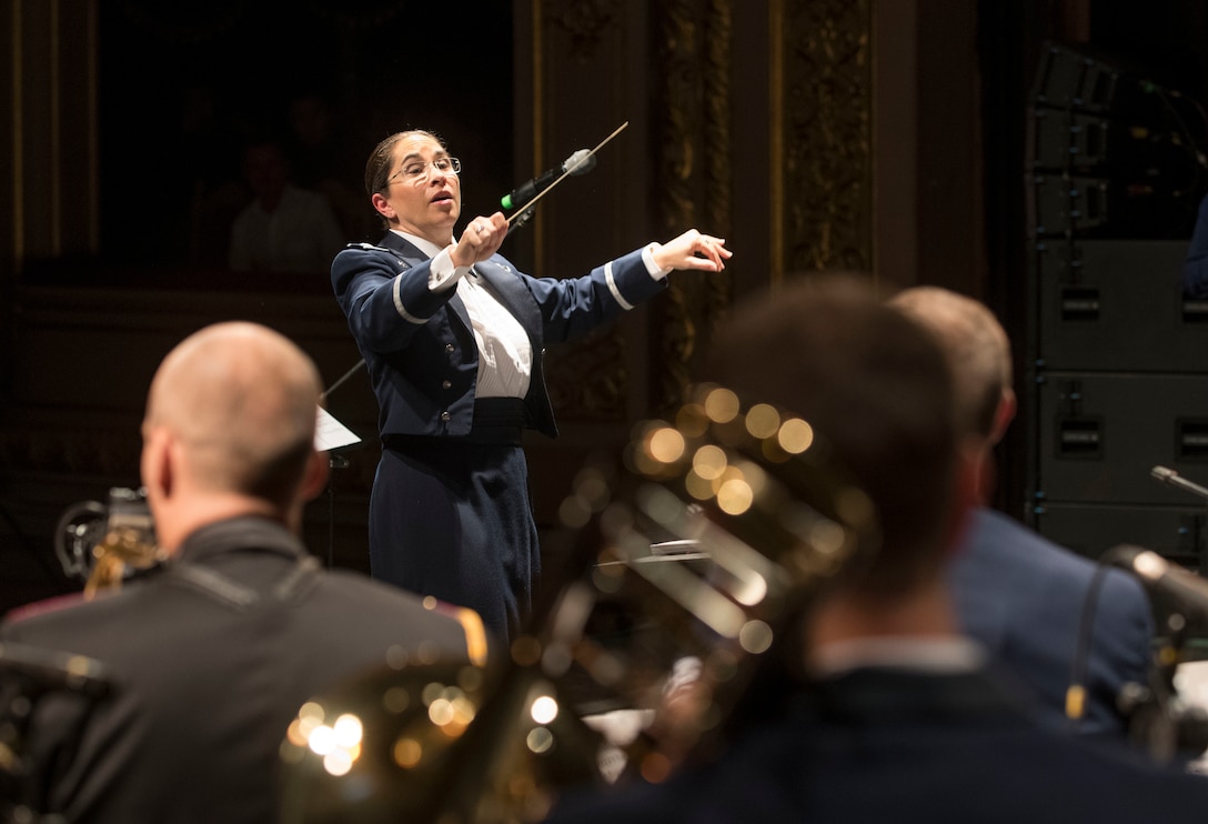 An Air Force band conductor uses a baton to direct musicians.