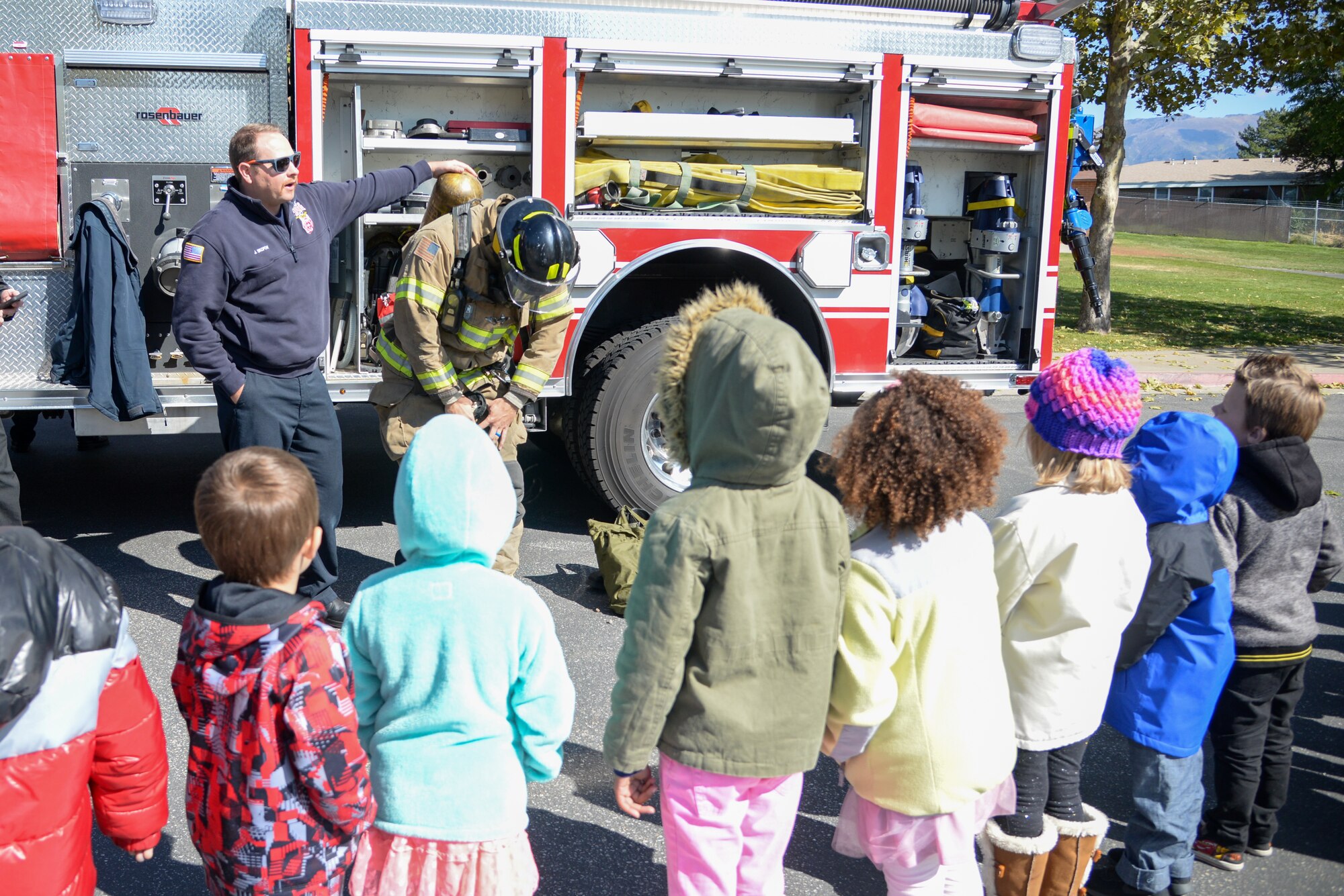 (Left to right) Jeffrey Skopow and Reagan Marcotte, Fire and Emergency Services at Hill Air Force Base, Utah, demonstrate firefighting equipment for Hill Field Elementary students Oct. 10, 2019, in front of the department’s fire engine. This was one of the numerous outreach events base firefighters sponsored for Fire Prevention Week Oct. 6-12. (U.S. Air Force photo by Cynthia Griggs)