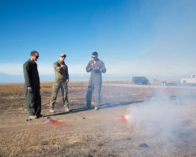 Staff Sgt. David Chorpeninng, 366th Fighter Wing survival, evasion, resistance and escape specialist, explains the differences between the illumination and smoke ends of the MK-124 marine smoke and illumination signal to Capt. Scott Hatter and Capt. Tyler Ludwig, 389th Fighter Squadron aircrew, Sept. 26, 2019, at Saylor Creek Bombing Range, Idaho.