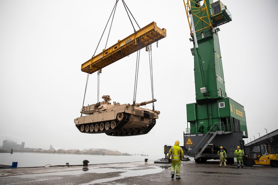 A large crane lifts a tank off the ground.