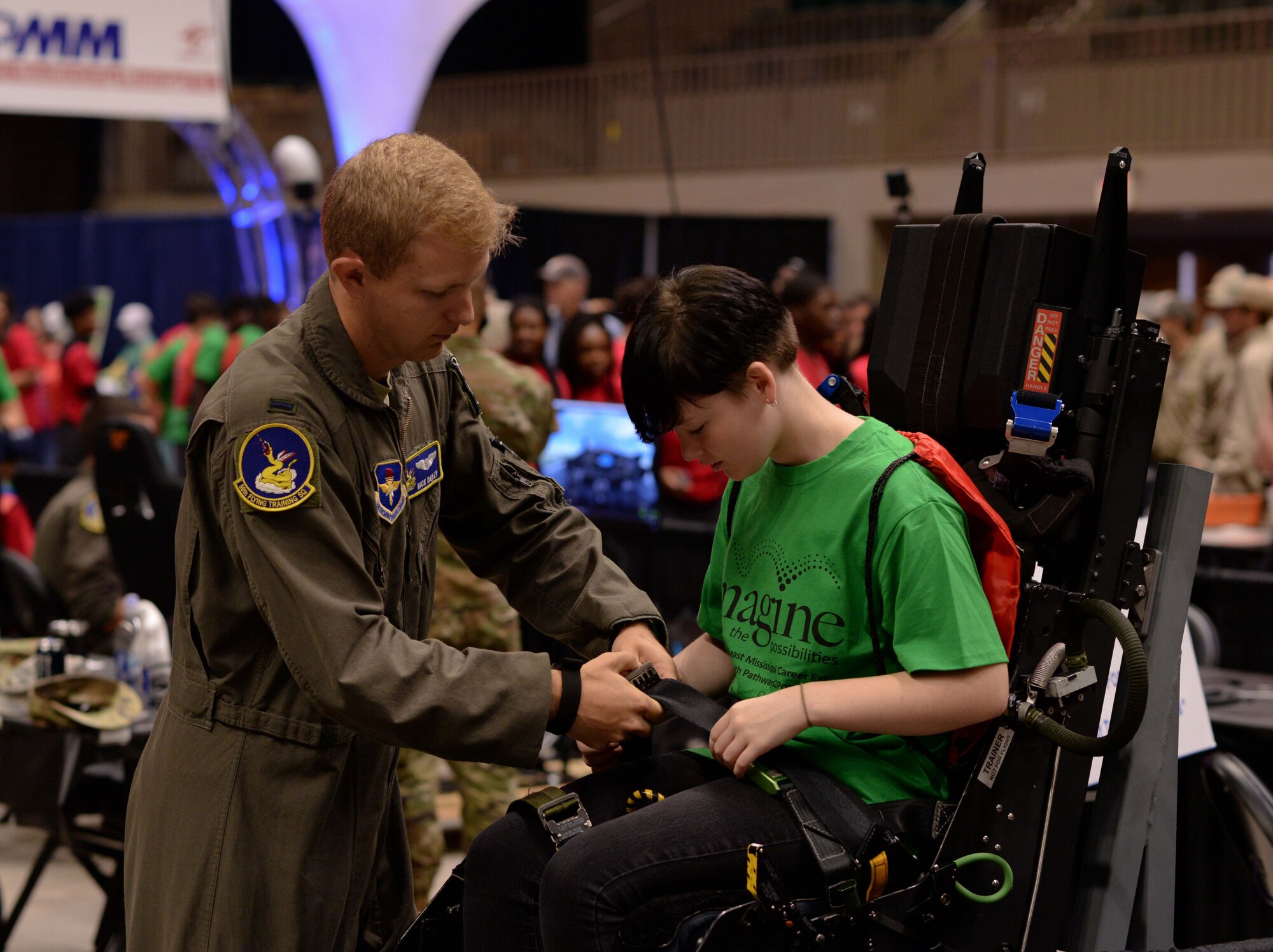 First Lt. Nicholas Bailey, 50th Flying Training Squadron instructor pilot at Columbus Air Force Base, Miss., shows a student how to strap into a pilot seat during the Imagine the Possibilities Career Expo Oct. 1, 2019, at the BancorpSouth Arena in Tupelo. Nearly 100 Airmen from Columbus AFB showcased 13 Air Force career fields to more than 7,200 eighth graders during the expo from Oct. 1-3. (U.S. Air Force photo by Airman Davis Donaldson)