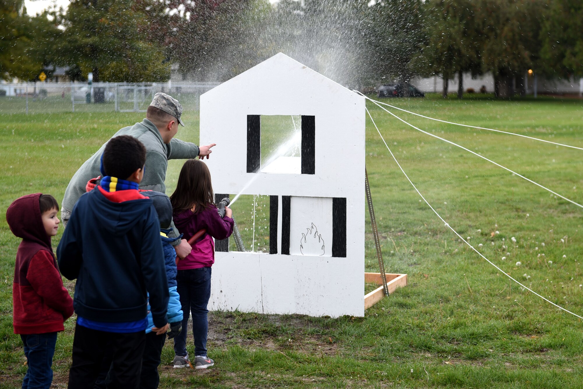 Staff Sgt. Logan Crytzer, 92nd Civil Engineer Squadron firefighter, shows base children how firefighters use fire hoses to put out a house fire at Fairchild Air Force Base, Washington, Oct. 8, 2019.