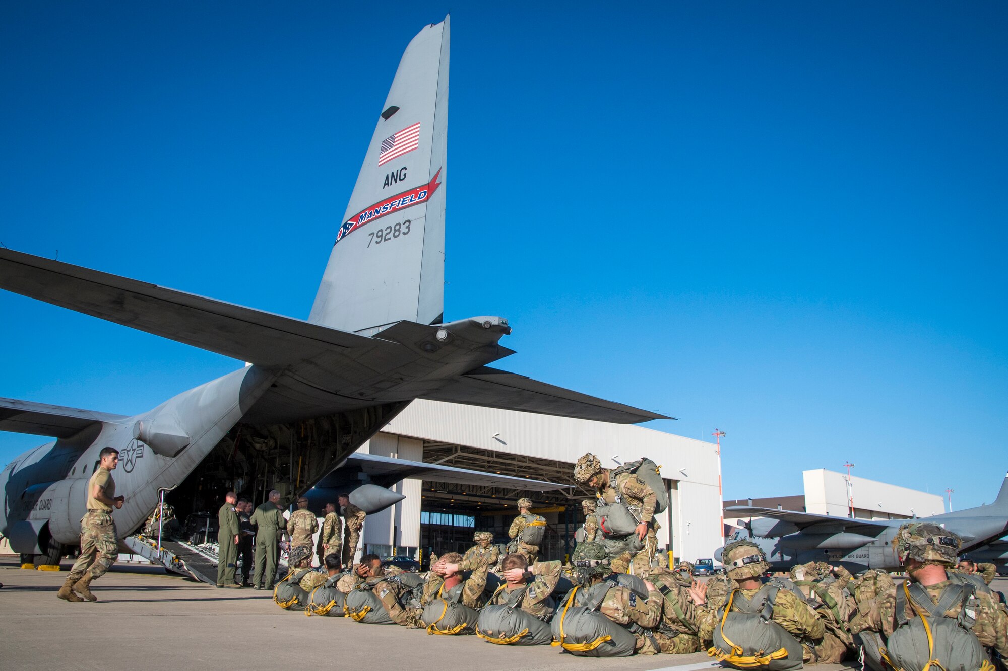 Photo of military members waiting in line to board a C-130