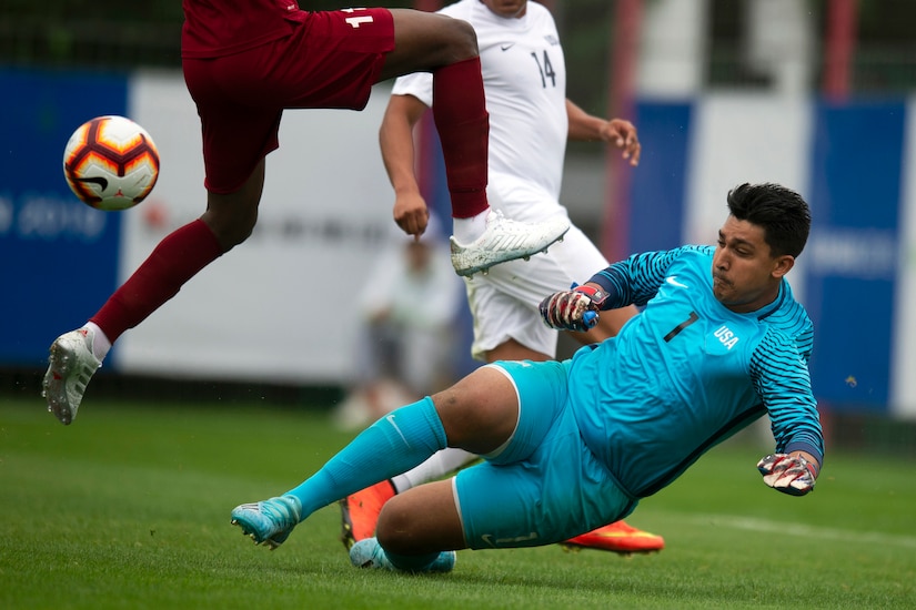 Blue-clad soccer goalie slides while making a save.