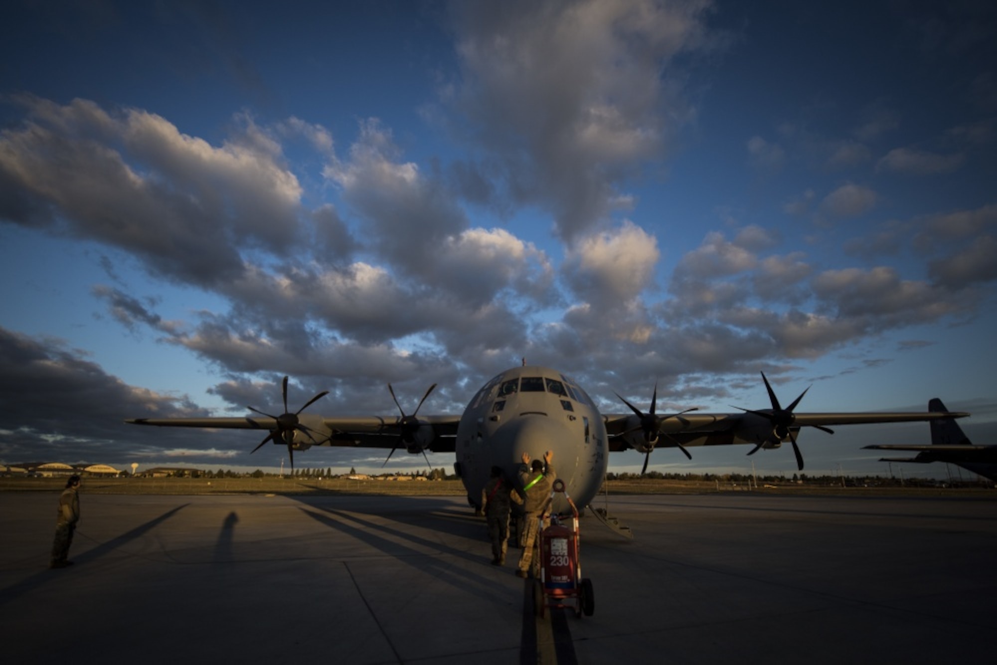 People stand in front of a C-130J.