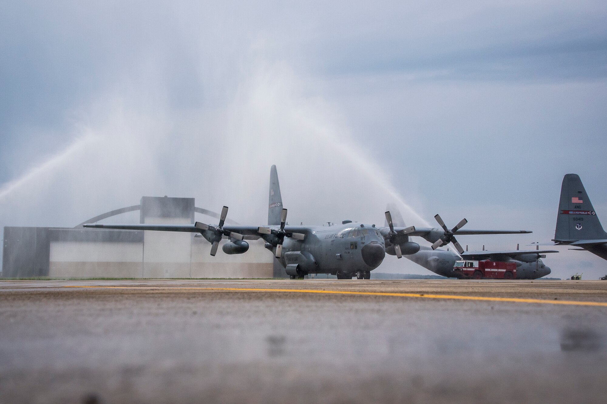 Photo of fire trucks spraying water on a C-130