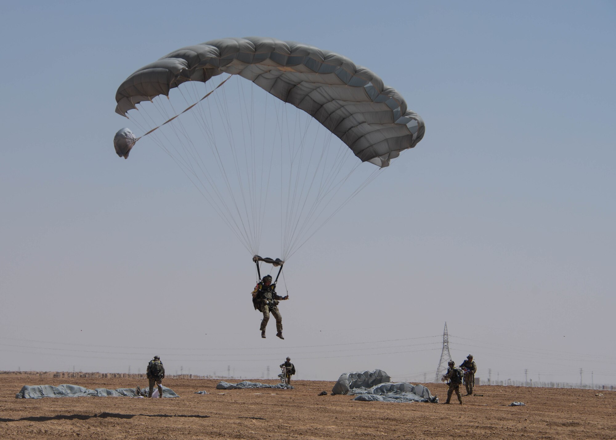 A participant in the Friendship Jump during Exercise Eager Lion parachutes to the ground while other jumpers collect their parachutes in Jordan on Sept. 5, 2019.