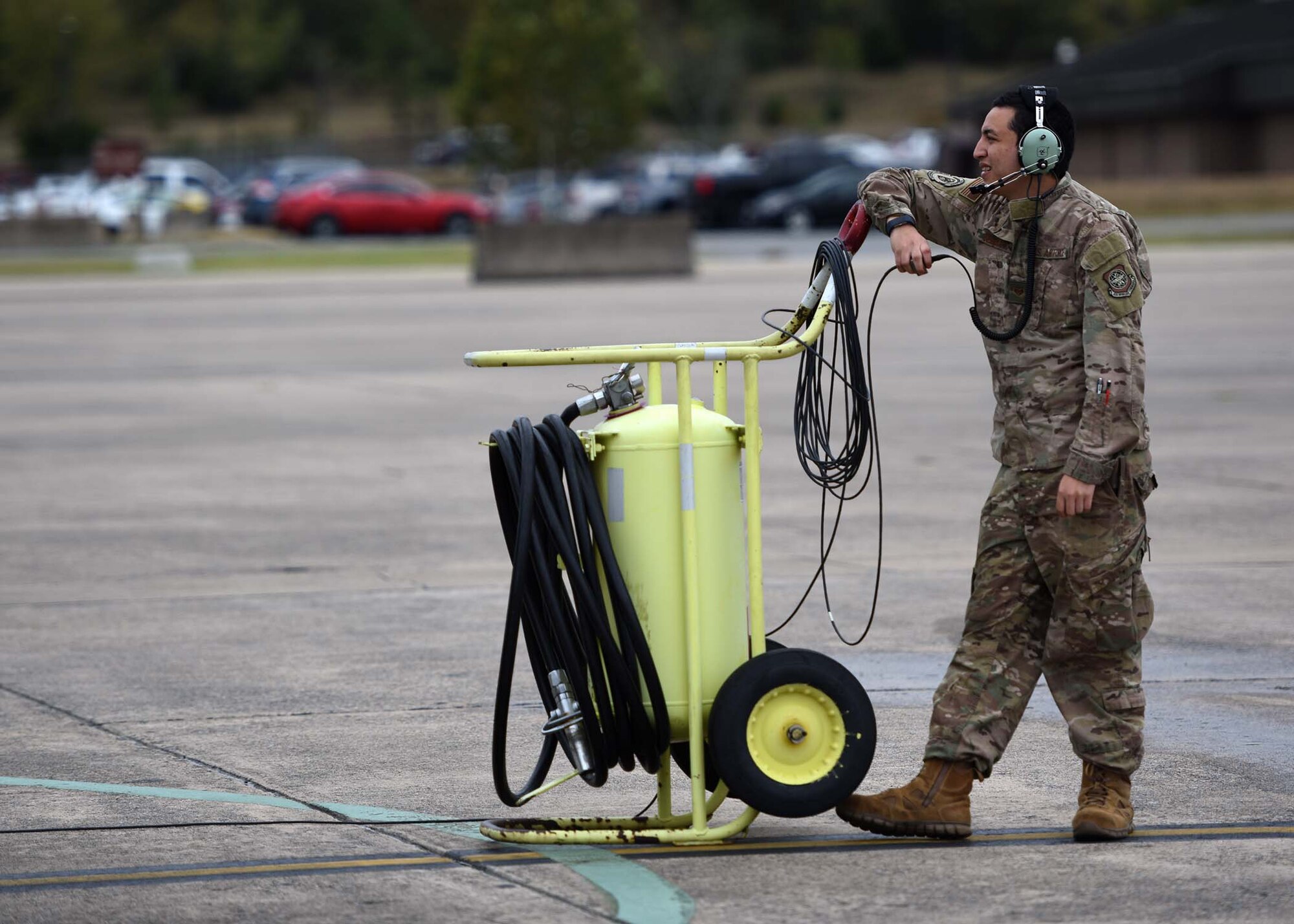 An Airman stands next to a big metal tank.