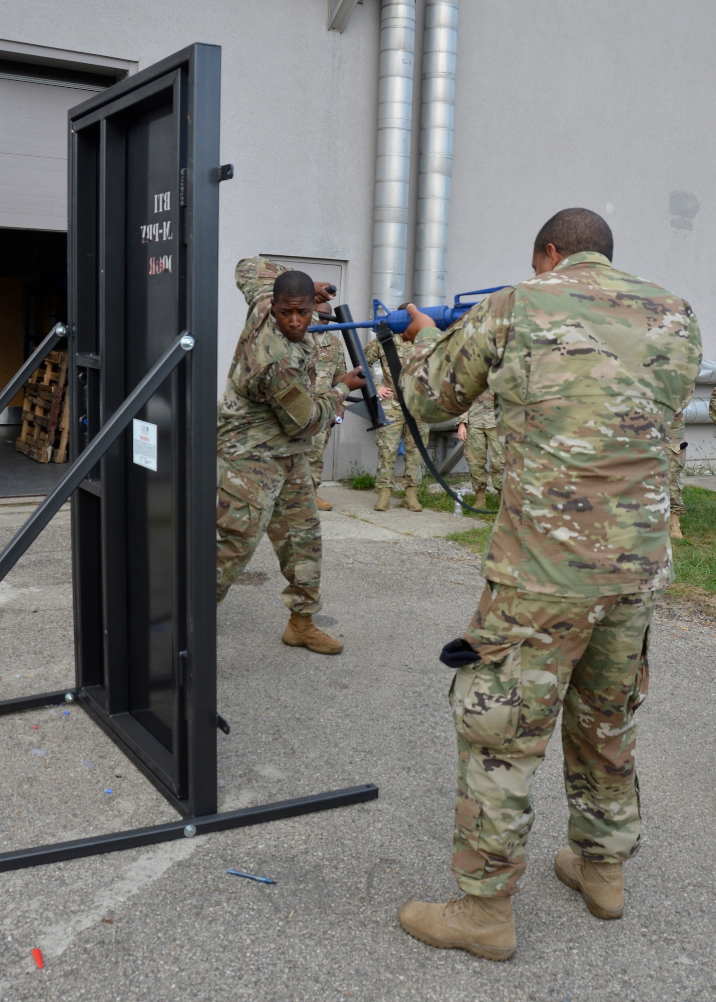 Senior Airman Daryn Weatherspoon, fire team member, 445th Security Forces Squadron, takes a swing at forcing open a metal training door outside the squadron on September 8, 2019 as Staff Sgt. Andrew Swasey, fire team member, looks on. The training, designed to give Airmen the opportunity to practice breaching locked doors, included several types of tools and simulated various team dynamics. (U.S. Air Force photo/1st Lt. Rachel Ingram)
