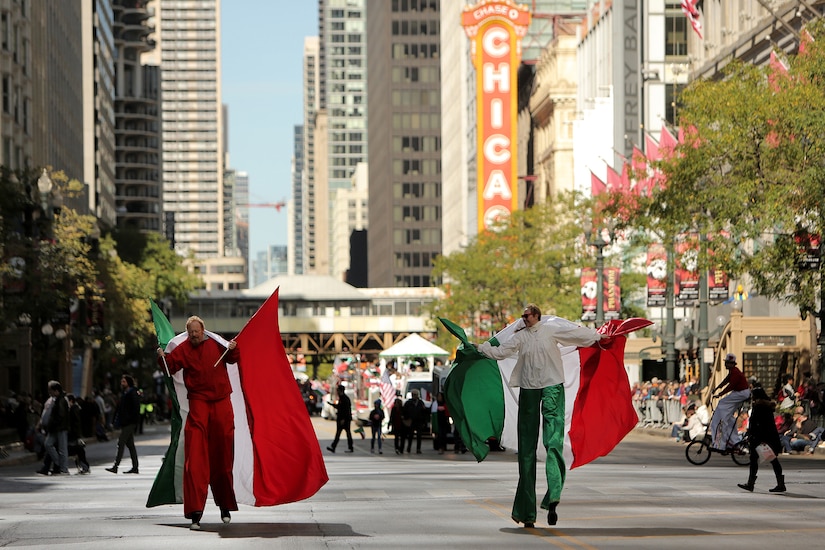 Parade participants walk on stilts, carrying large Italian flags, during the 2019 67th Annual Columbus Day Parade in the City of Chicago, October 14, 2019.