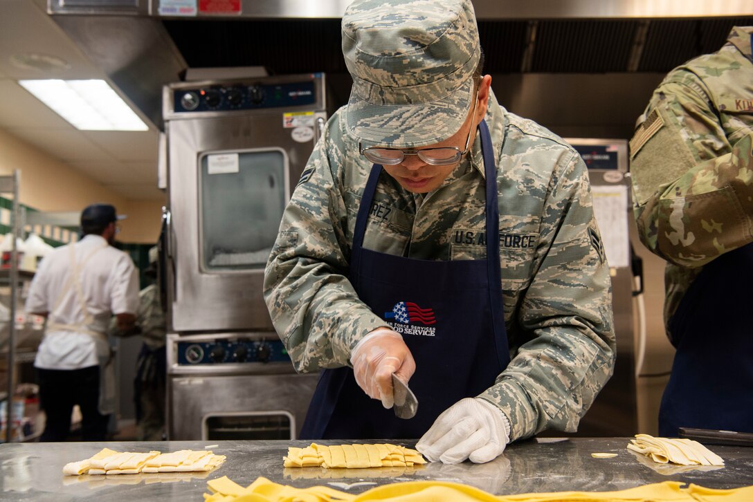 Airman 1st Class Juan Miguel Perez, 90th Force Support Squadron food service apprentice, cuts freshly prepared sheets of pasta to be layered into the final dish after cooking during a competition Oct. 15, 2019, at F.E. Warren Air Force Base, Wyo. Each team was required to cook a main dish featuring the mystery ingredient lamb within a one-hour time limit. (U.S. Air Force photo by Senior Airman Abbigayle Williams)