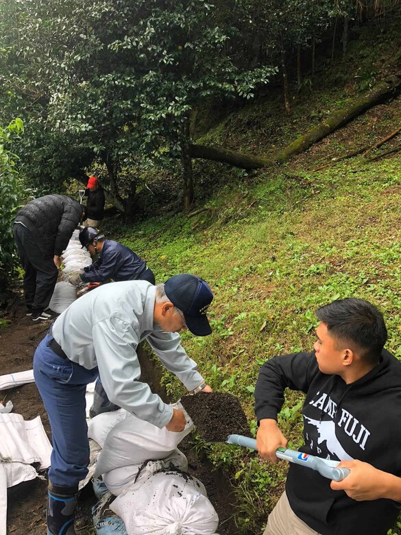 地元住民と協力し、土のうを住宅地裏にある溝に沿って並べる海兵隊員の。台風19号で被災した小山町で15日、米海兵隊キャンプ富士の隊員12人がボランティアで支援活動に取り組みました。