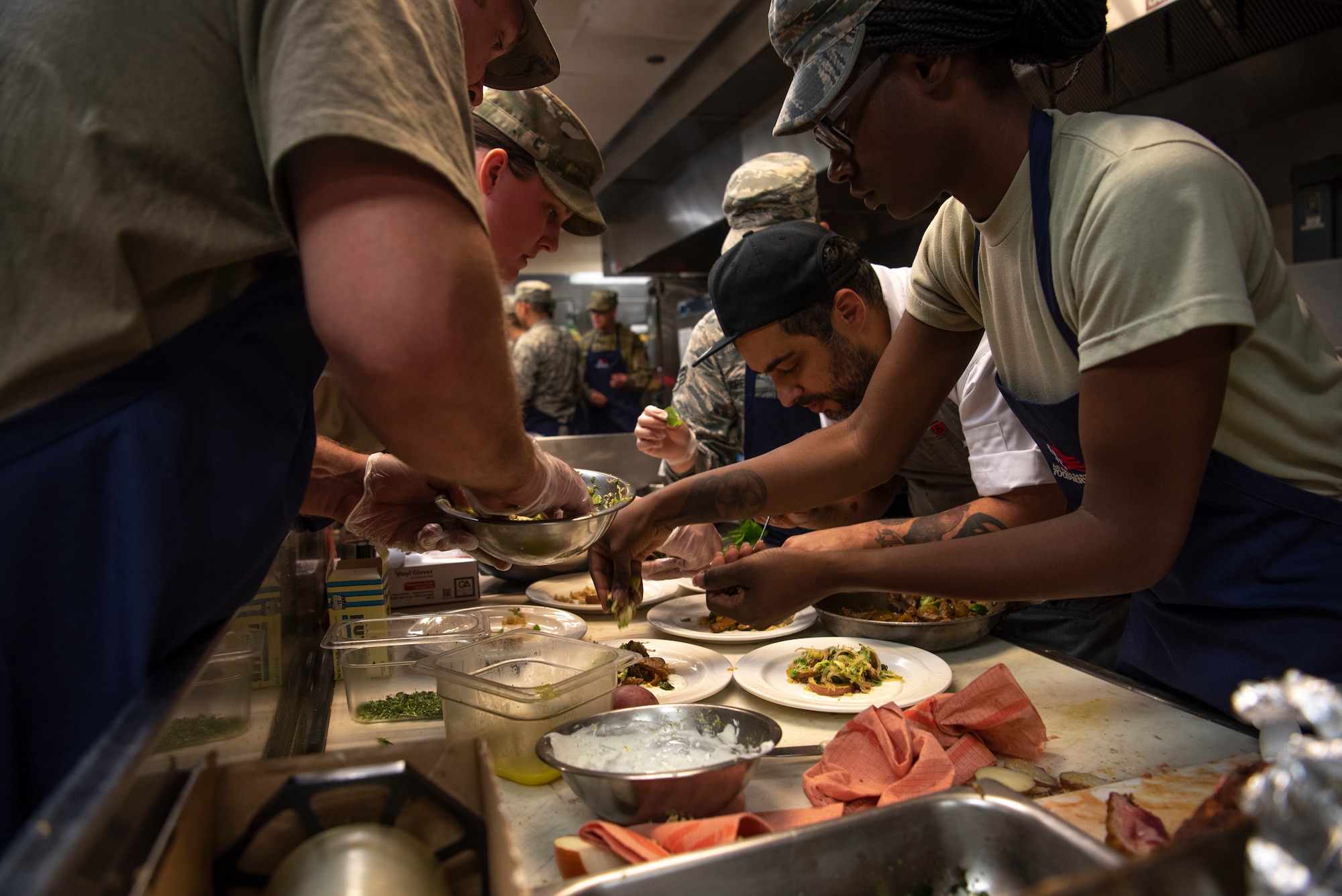 The Startled Koala team has all hands on deck to plate six portions of their lamb dish during a cooking competition Oct 15, 2019, at F.E. Warren Air Force Base, Wyo. The dish was comprised of quinoa, “European” ranch, lamb, Brussles sprouts and salad garnished on top. (U.S. Air Force photo by Senior Airman Abbigayle Williams)