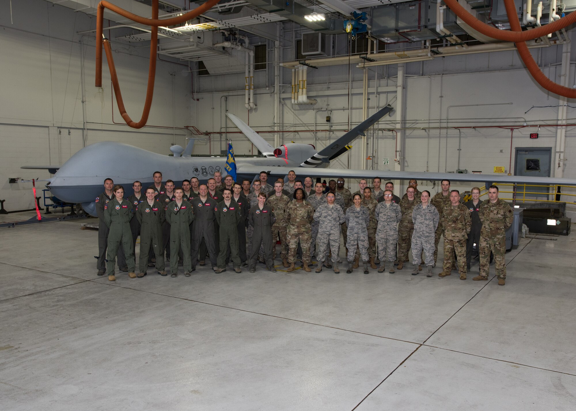 Airmen with the 20th Attack Squadron pose for a group photo in front of an MQ-9 Reaper, at Whiteman Air Force Base, Missouri, June 17, 2019. The 20th ATKS is a geographically separated unit that falls under the 432nd Wing/432nd Air Expeditionary Wing and supports combatant commanders in operations abroad. (U.S. Air Force photo by Airman 1st Class Parker J. McCauley)