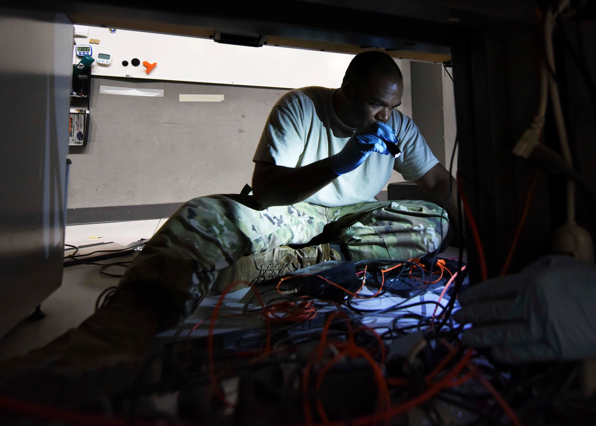 Master Sgt. Thaddaus Zeno, 609th Expeditionary Air Communications Squadron tactical transmission systems section chief, performs communication maintenance and IT infrastructure upgrades on the Combat Operations Division floor at the Combined Air Operations Center, Al Udeid Air Base, Qatar, Sept. 28th, 2019. The CAOC relinquished air power command and control operations to the Total Force 609th Air Support Squadron at Shaw Air Force Base in South Carolina for a 24-hour period, allowing the 609th EACOMS to perform their mission. (U.S. Air Force photo by Staff Sgt. Soo Kim)
