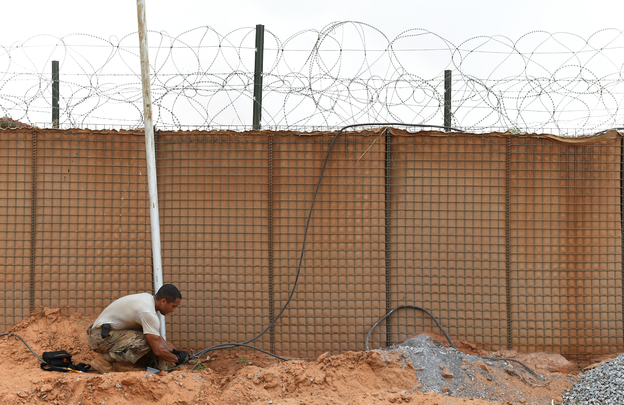 U.S. Air Force Tech. Sgt. Guillermo Cajigas, 768th Expeditionary Air Base Squadron Power Production and Electrical Systems section lead, connects a new cable for perimeter lighting at Nigerien Air Base 101, Niamey, Niger, Oct. 10, 2019. The cable was rerouted to make way for the foundation of the base’s new gym facilities. (U.S. Air Force photo by Staff Sgt. Alex Fox Echols III)