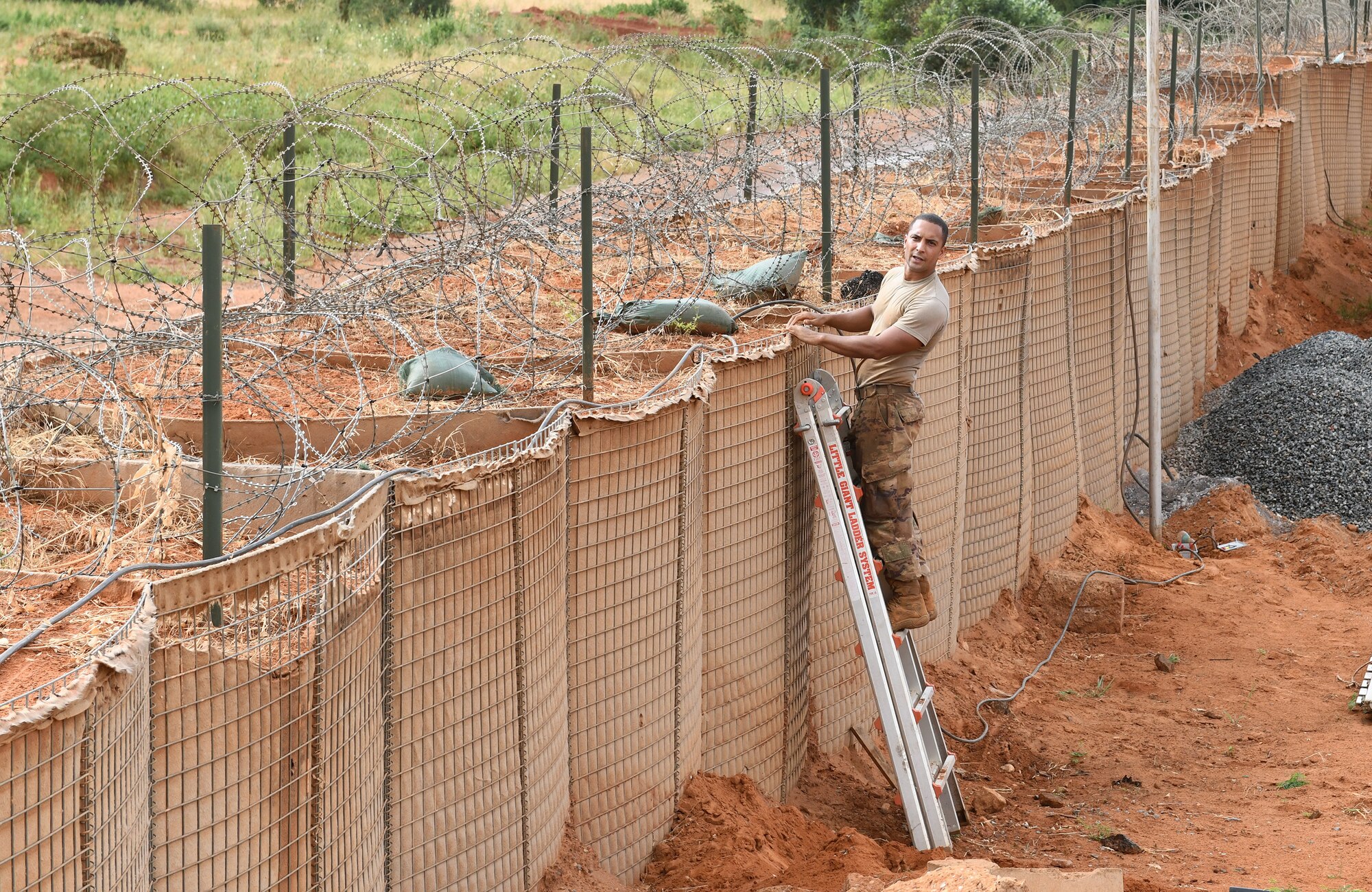 U.S. Air Force Tech. Sgt. Guillermo Cajigas, 768th Expeditionary Air Base Squadron Power Production and Electrical Systems section lead, secures a new cable for perimeter lighting at Nigerien Air Base 101, Niamey, Niger, Oct. 10, 2019. The cable was rerouted to make way for the foundation of the base’s new gym facilities. (U.S. Air Force photo by Staff Sgt. Alex Fox Echols III)