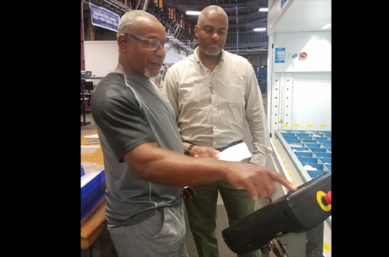 John Horton watches William Bland demonstrate an automated product retrieval system.