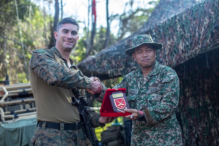 U.S. Marine Corps Maj. Kyle Padilla, the company commander with Lima Company, Battalion Landing Team, 3/5, 11th Marine Expeditionary Unit, receives a plaque from a member of the Malaysian Armed Forces. U.S. Marines and Sailors joined Malaysian Armed Forces for exercise Tiger Strike 2019 where both forces participated in jungle survival, amphibious assault, aerial raids, and combat service support training and cultural exchanges