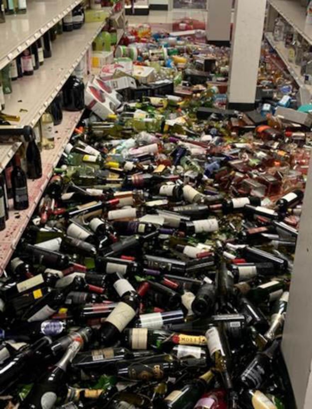 Hundreds of glass wine bottles are on the floor of a retail facility.