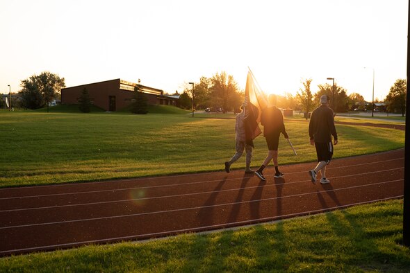 Senior Airman Denise Arabie, 319th Operations Support Squadron Air Traffic Control Apprentice, Airman First Class Jurgen Vasquez, 319 OSS Air Traffic Control, and Master Sgt. Scott Hall, 319 OSS Assistant Chief Controller, walk during the 24 hour prisoner of war and missing in action recognition day relay Sept. 25, 2019 on Grand Forks Air Force Base, North Dakota. Airmen took turns bearing the POW MIA guidon and taking laps around the outdoor and indoor track to honor and remember those past and current POW MIA servicemembers. (U.S. Air Force photo by Senior Airman Elijaih Tiggs)