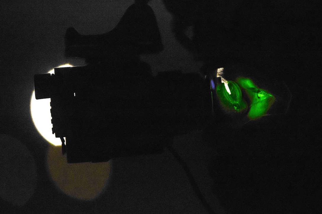 A Marine in a dark room with a green light shining on his eyes.