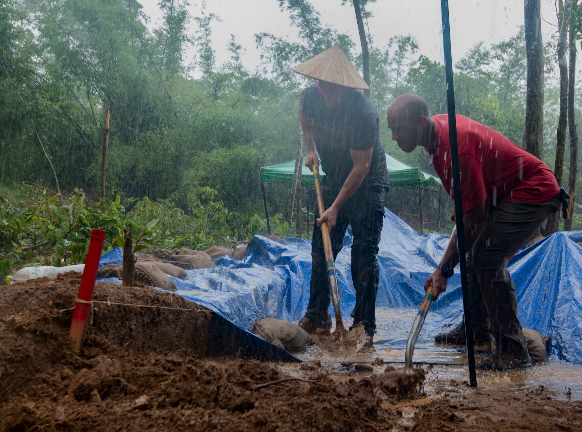 U.S. Army Staff Sgt. Joel Brigham, Defense POW/MIA Accounting Agency (DPAA) medic, left, and U.S. Marine Corps Sgt. Brandon Swain, DPAA recovery noncommissioned officer augmentee, dig trenches for overflowing rain water during a DPAA recovery mission in Khammouan province, Lao People’s Democratic Republic, May 23, 2018. DPAA team members deployed to the area in hopes of locating U.S. service members who went missing from the Vietnam War. The mission of DPAA is to provide the fullest possible accounting for our missing personnel to their families and the nation. (U.S. Air Force photo by Staff Sgt. Mikaley Kline)