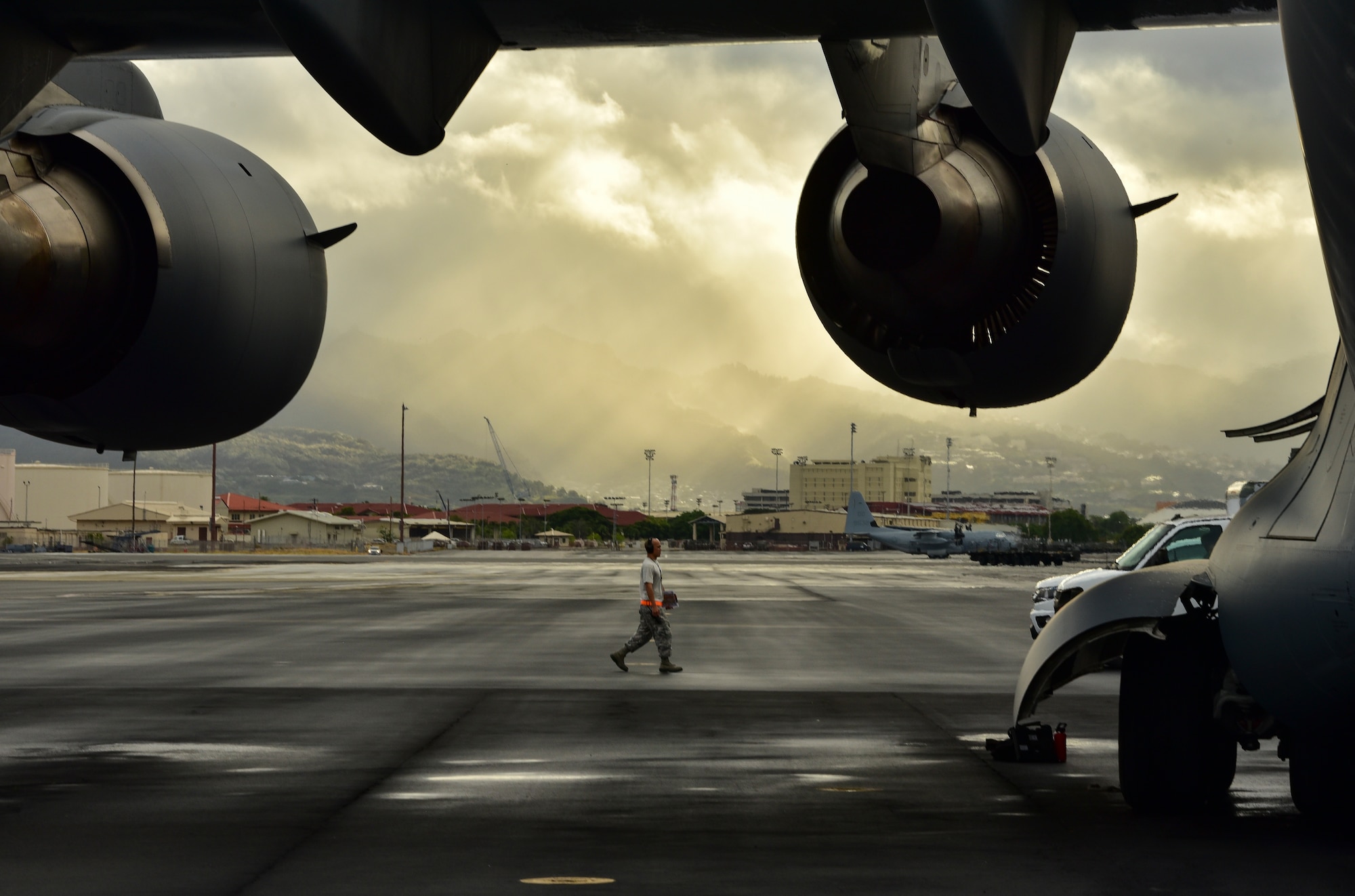An Airman from the 15th Aircraft Maintenance Squadron walks on the flight line before a heavy rainfall at Joint Base Pearl Harbor-Hickam, Hawaii, Sept. 23, 2019. The Airman was greeting a C-17 Globemaster III that had just returned from Papua New Guinea with personnel from the Defense POW/MIA Accounting Agency (DPAA). The team was returning with possible remains of service members lost during WWII. DPAA’s mission is to provide the fullest possible accounting of our missing personnel to their families and the nation. (U.S. Air Force photo by Staff Sgt. Apryl Hall)