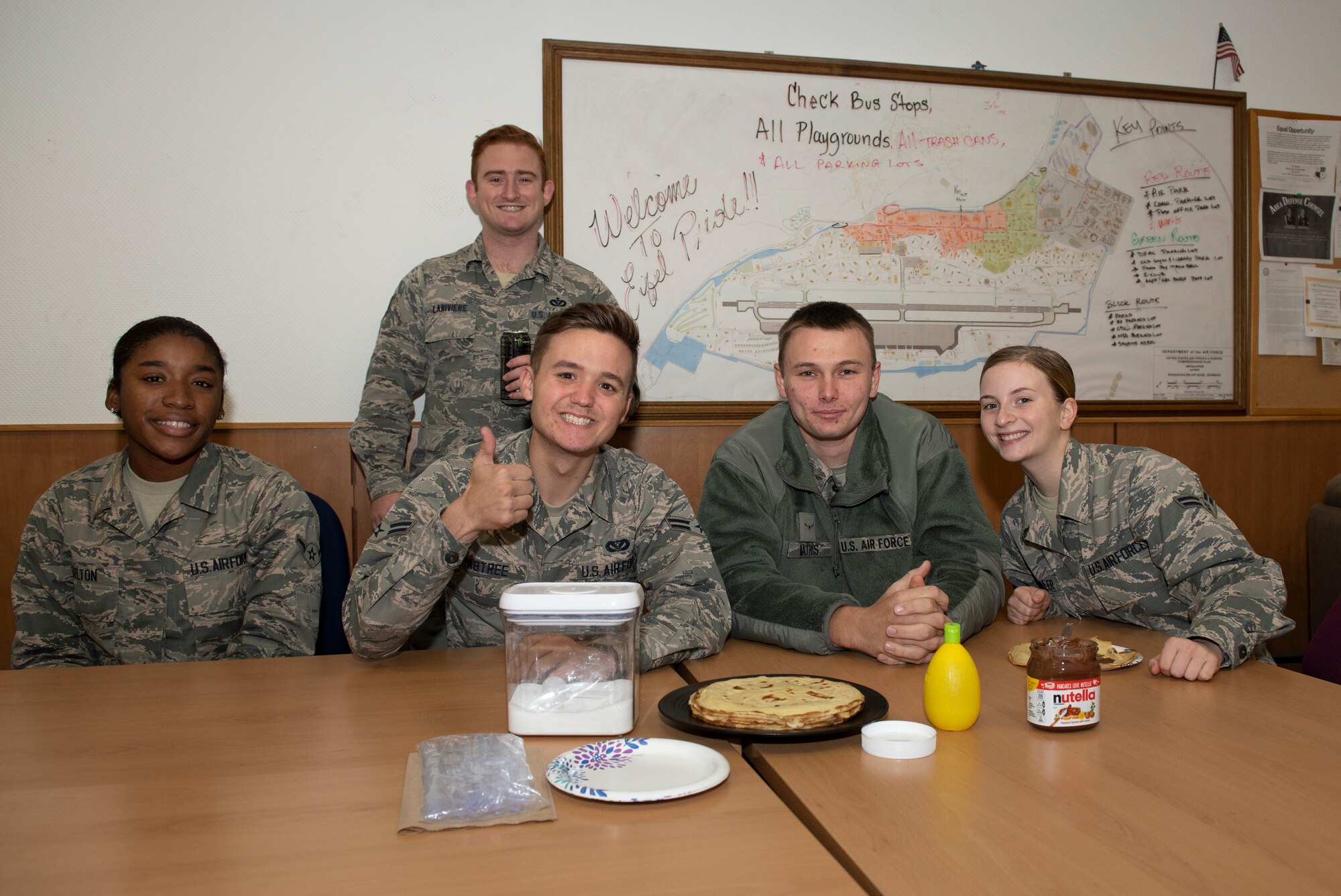 U.S. Air Force Staff Sgt. Matthew Lariviere, 52nd Civil Engineer Squadron NCO in-charge of Eifel Pride, rear, and Airmen enrolled in the Eifel Pride program pose for a group photo with homemade crepes provided by Lariviere's wife, Célia, in the Eifel Pride room on Spangdahlem Air Base, Germany, 16 Oct. 2019. Célia hoped to improve the morale of Airmen and make them feel at home with a homemade breakfast. (U.S. Air Force photo by Airman 1st Class Alison Stewart)