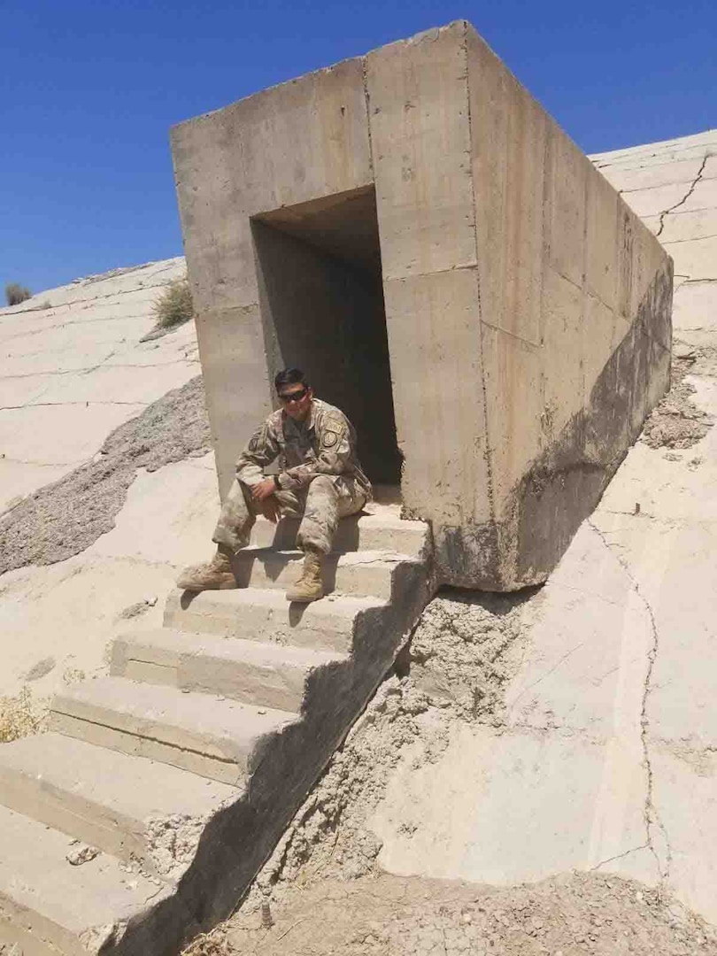 New York Army National Guard Sgt. Jhon Ortiz, deployed in support of the Baghdad Diplomatic Support Center, poses outside one of Saddam Hussein’s bunkers near Baghdad Airport, Iraq, in 2018. Ortiz developed a logistics tracking system to support the relocation of personnel, 114 vehicles and materials during the closing of the U.S. Embassy’s Basra Consulate. He received the U.S. Department of State Meritorious Honor Award Sep. 5, 2019, for his actions.