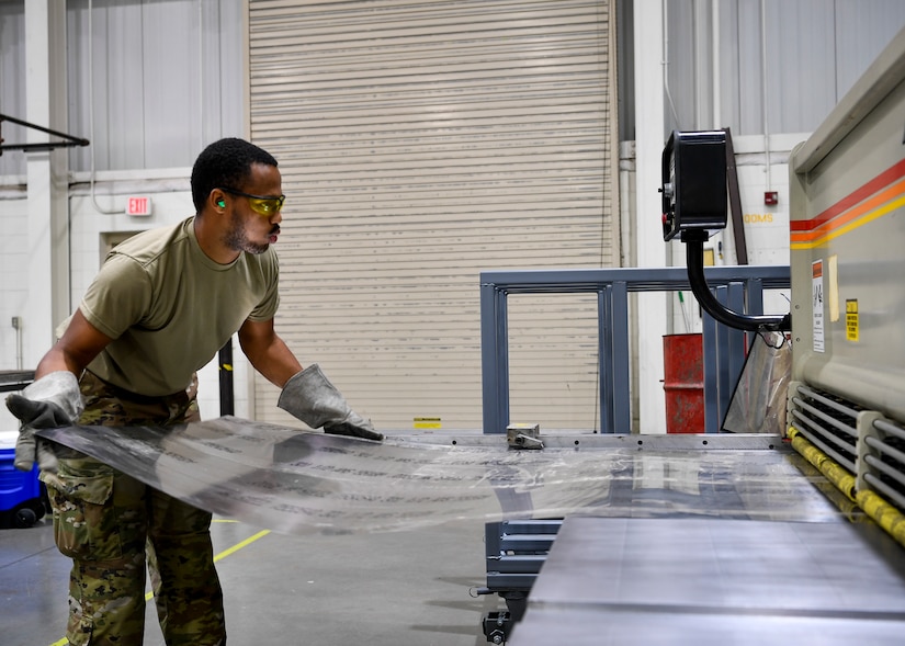 U.S. Air Force Senior Airman Armani Everson, 305th Maintenance Squadron Fabrication Flight aircraft structural maintenance journeymen, places a piece of sheet metal into a machine to be cut on Joint Base McGuire-Dix-Lakehurst, New Jersey, Oct. 16, 2019. Aircraft structural maintenance Airmen inspect structures and components to determine operational status and can use sheet metal on aircraft to ensure each plane is suited to fly at a moment’s notice. The mission of the 305th MXS is to enhance global response by providing world class systems, support equipment, munitions and aircraft maintenance. (U.S. Air Force photo by Senior Airman Jake Carter)